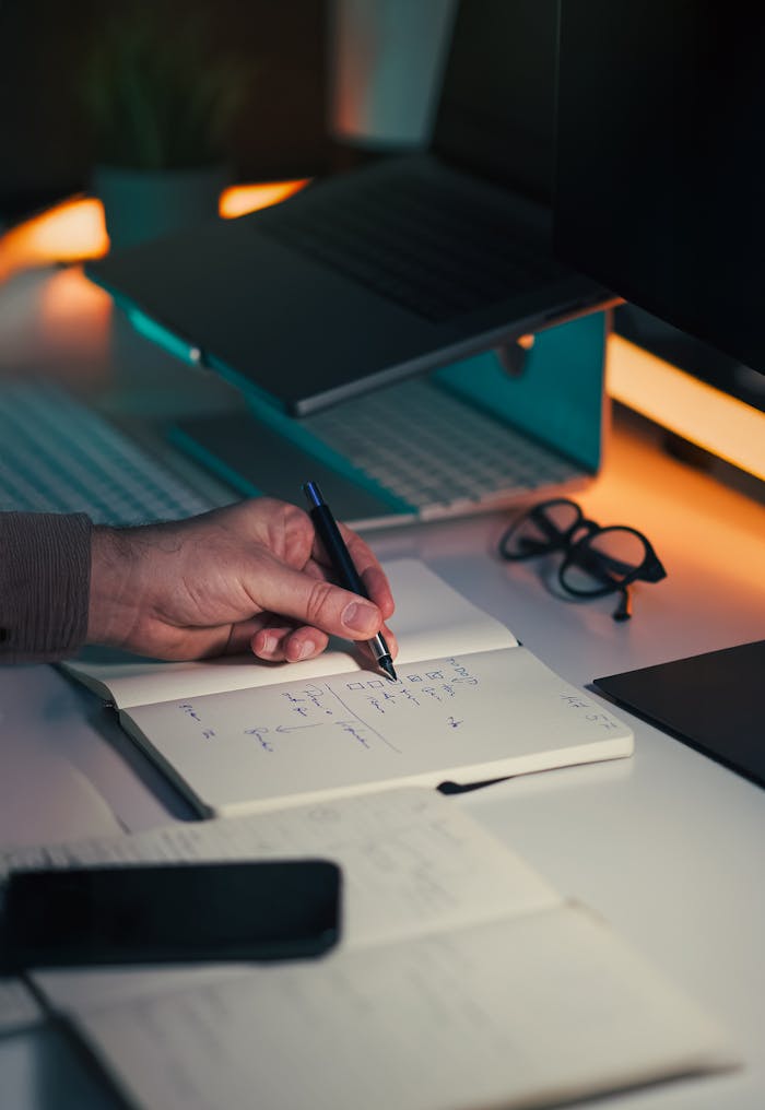 A detailed photo of a workspace focusing on productivity tools like a notebook, pen, and laptop.