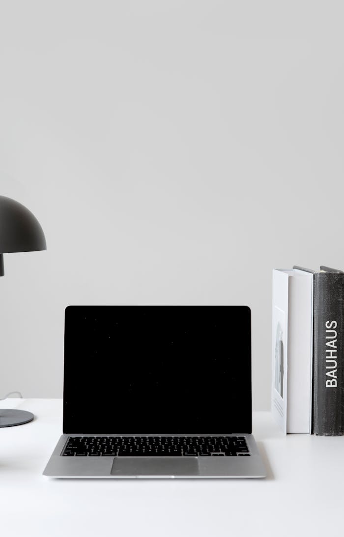 A clean, modern workspace with a laptop, desk lamp, and books on Bauhaus design.
